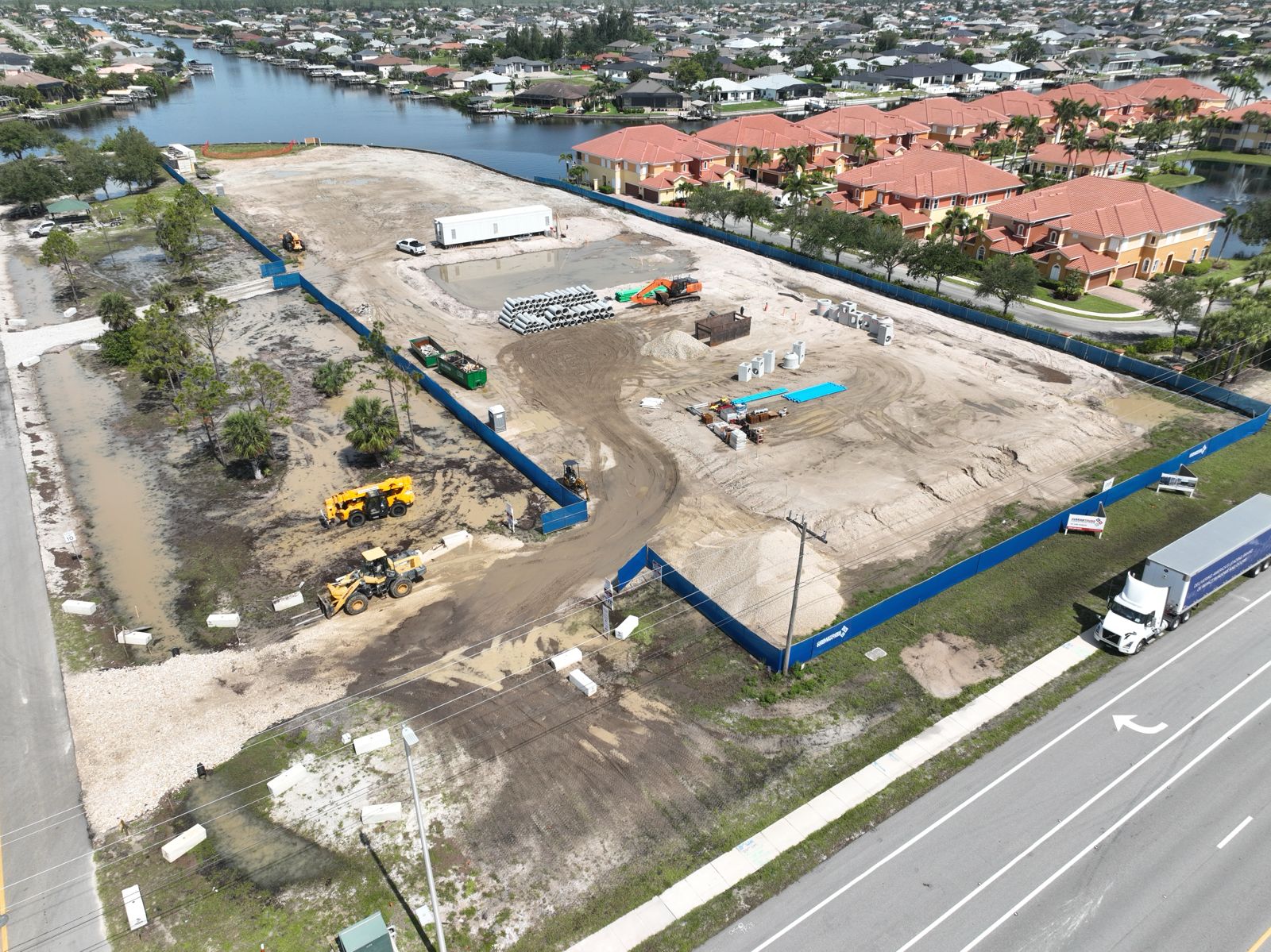 Lake Shadroe site at 218 Burnt Store Road South, Cape Coral — full site overview with pile driver and waterway, April 2026, Curran Young Construction